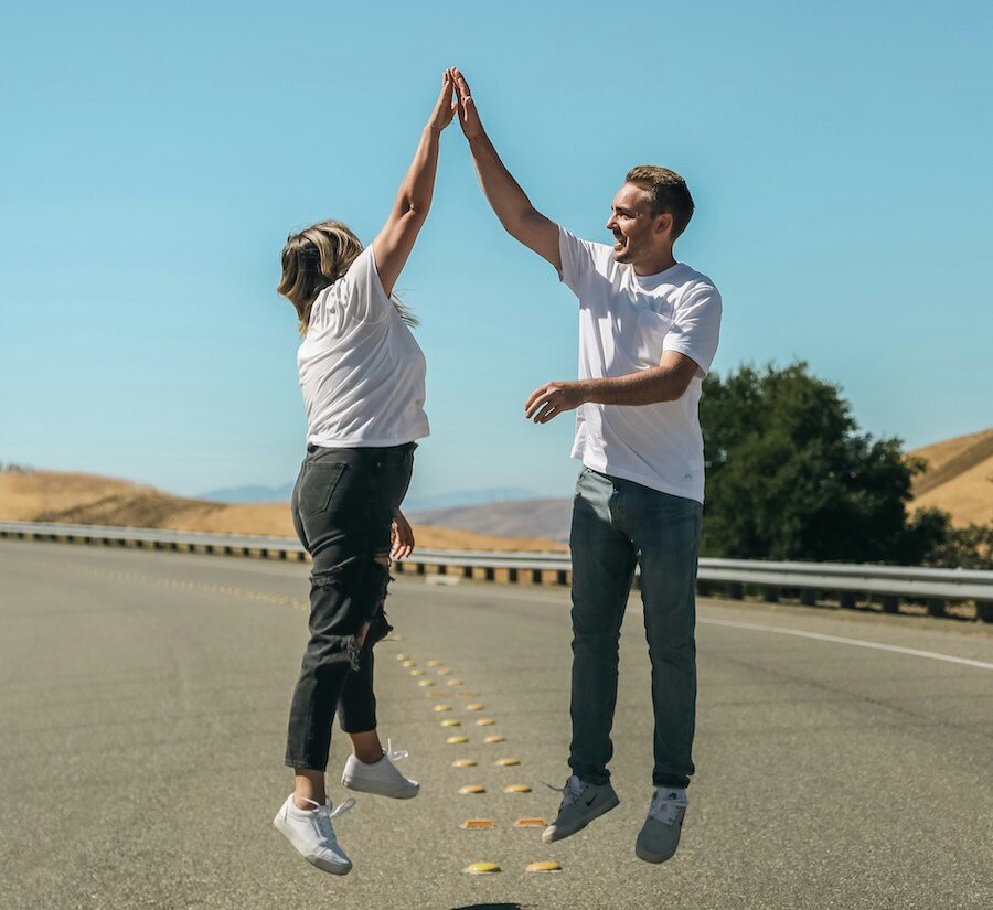 Two people giving each other a high five while jumping